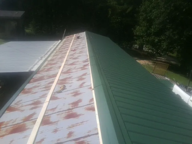 Old rusted panels beside newly installed green metal roofing — Wind Damage Roof Repair by Roofing Brothers in Smith