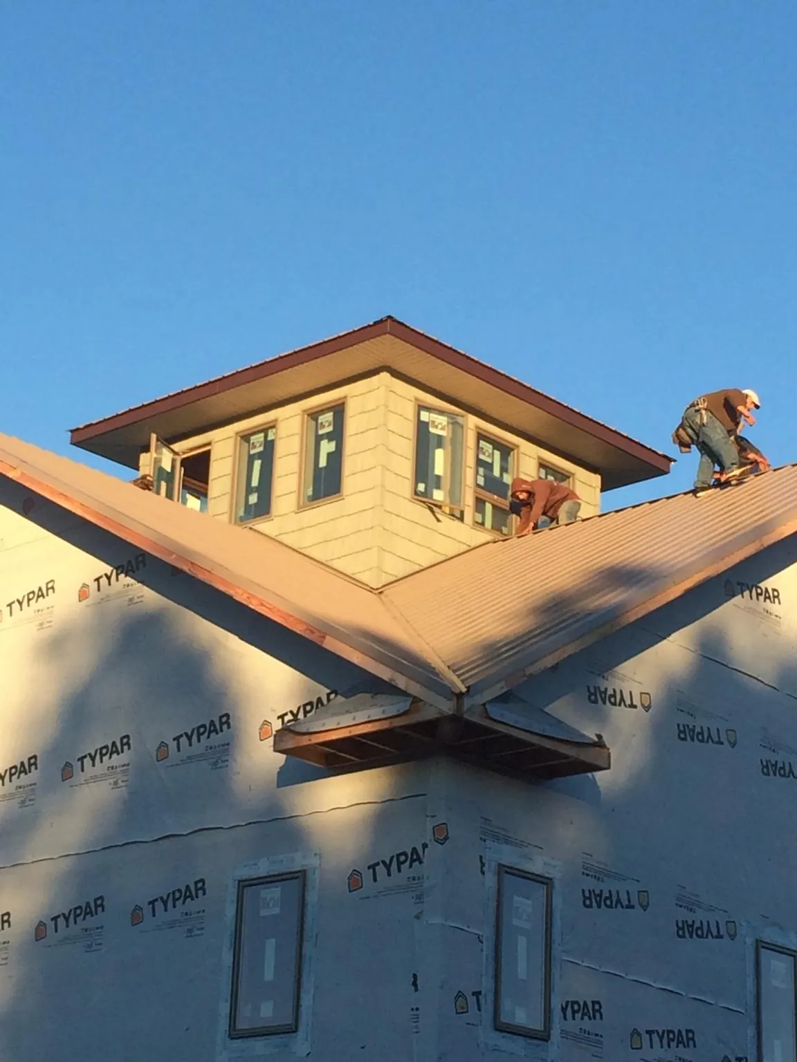 Roofers working around a rooftop cupola on a new metal roof at sunset — Roof Waterproofing in Smith by Roofing Brothers